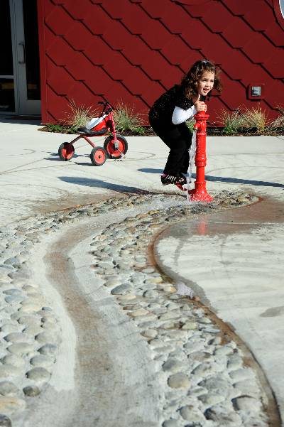 child playing with water pump outside at the early learning center