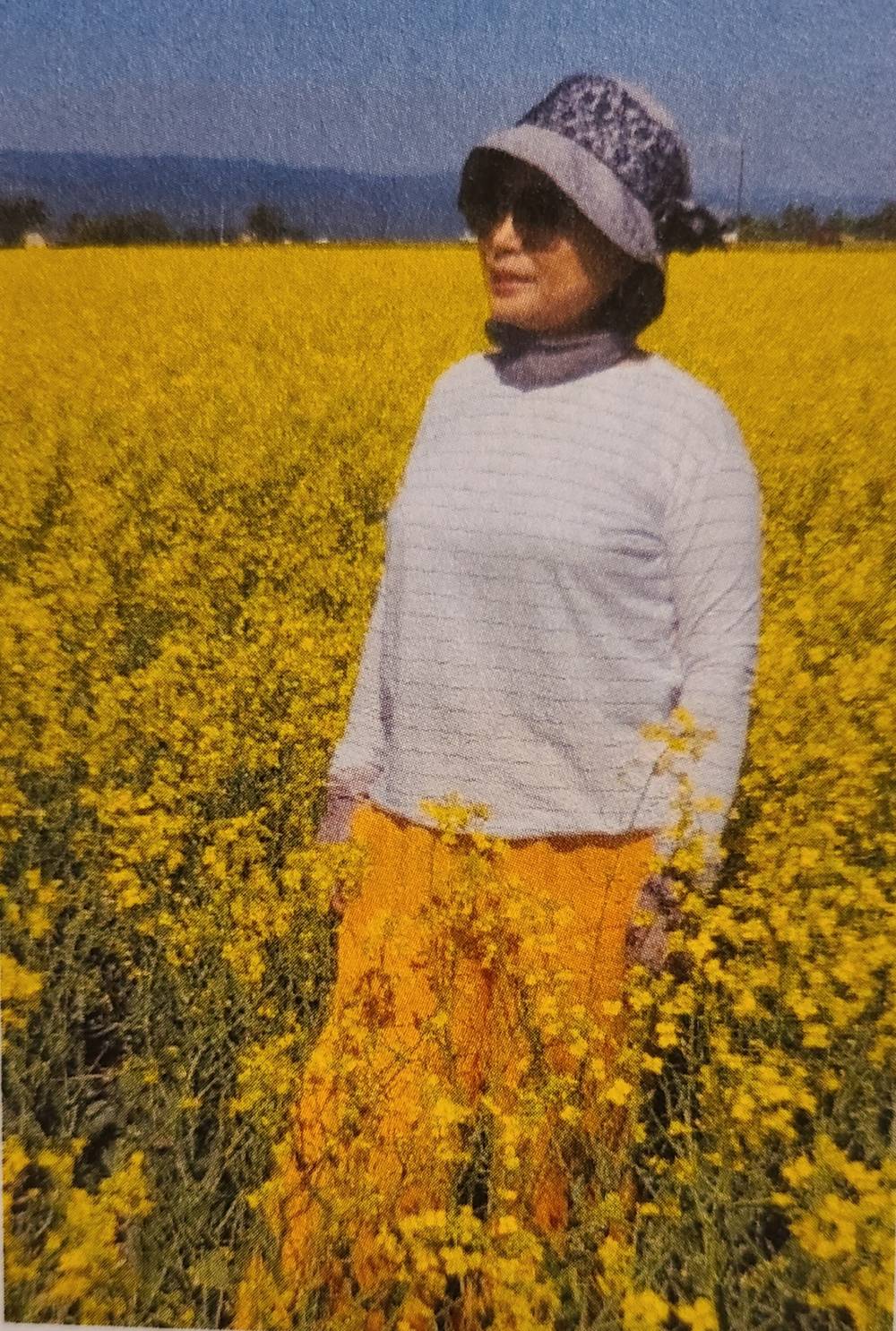 Filtered photo of Hannah Ra standing in a field of yellow flowers.