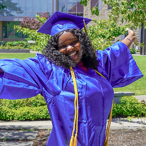 grad in blue regalia with arms outspread