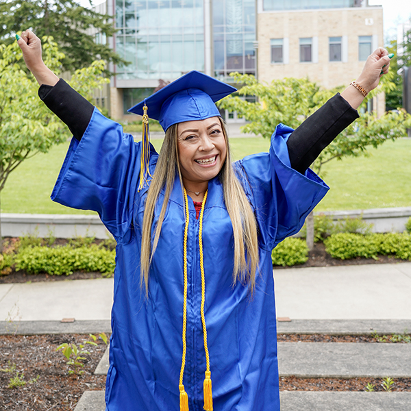 grad with blue regalia arms up