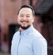 Man smiles wearing a light blue button up