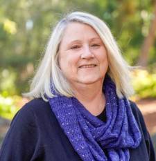 Woman smiles wearing a black shirt with purple scarf