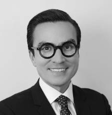 portrait photo of a man in a suit wearing glasses smiling