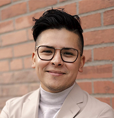 Man with glasses and dark hair smiling. 