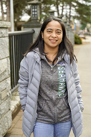 A woman in a grey coat on the TCC Bridge smiling. 